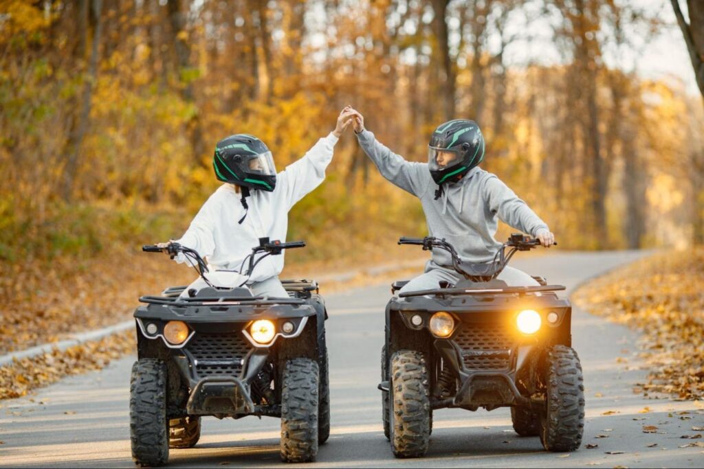 Two Young People On Quad Bikes High Fiving