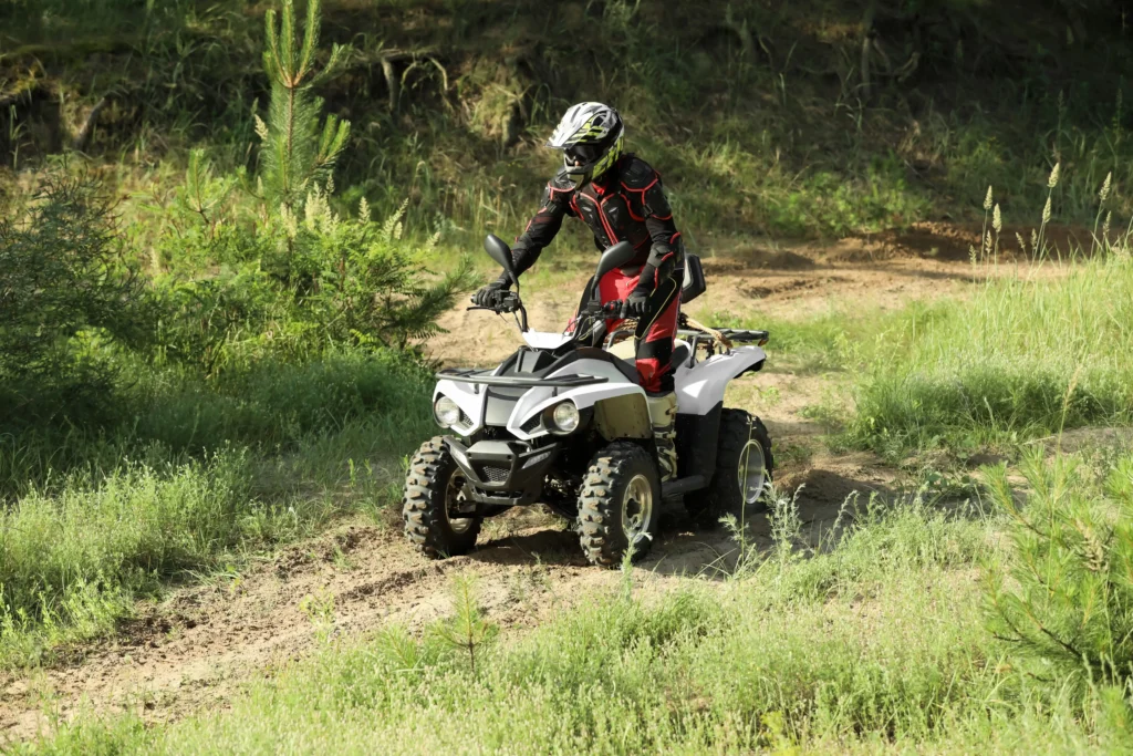 Young man driving an age appropriate quad bike on a sandy road