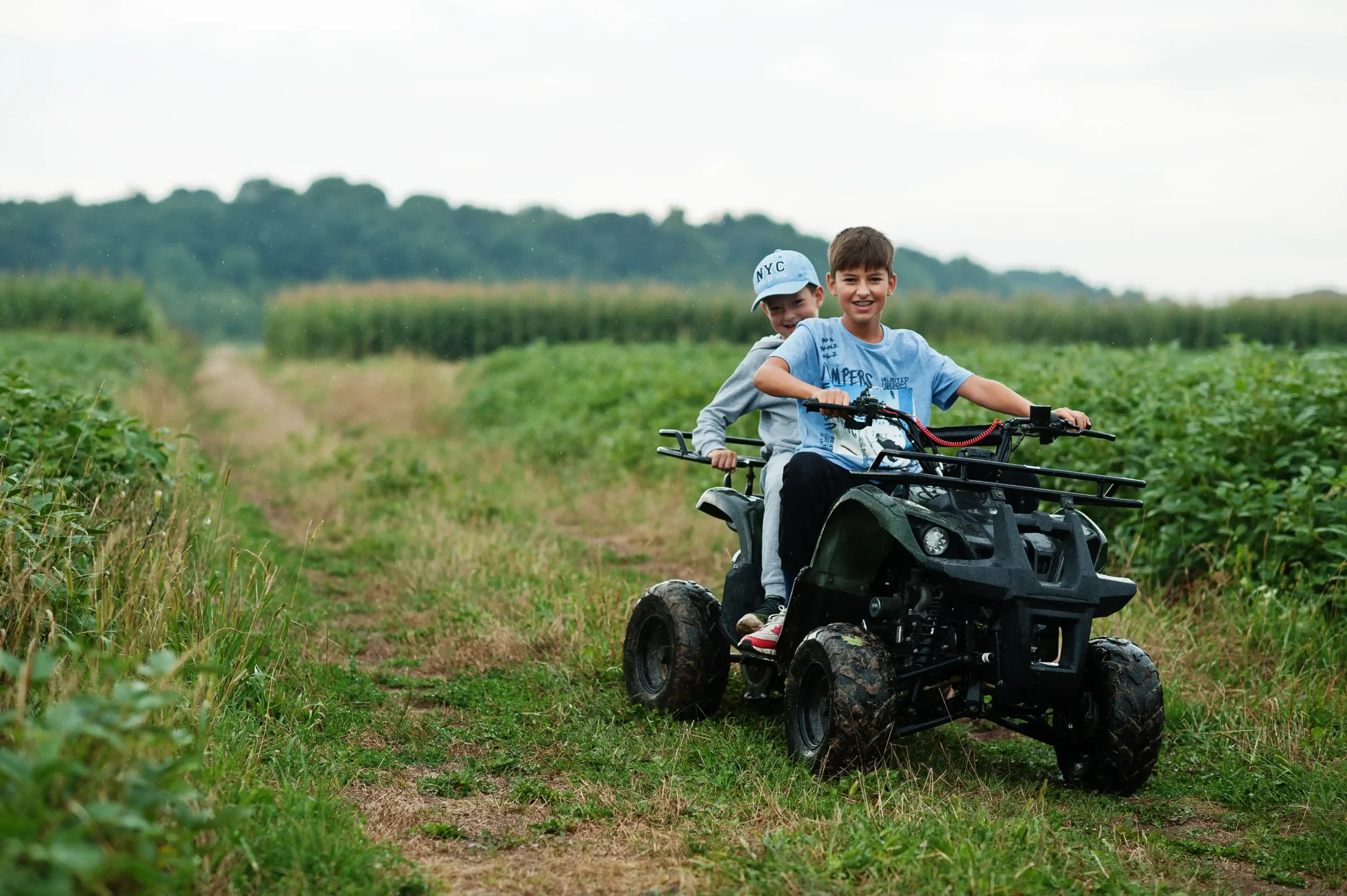 Two brothers driving a quad bike ATV in a field