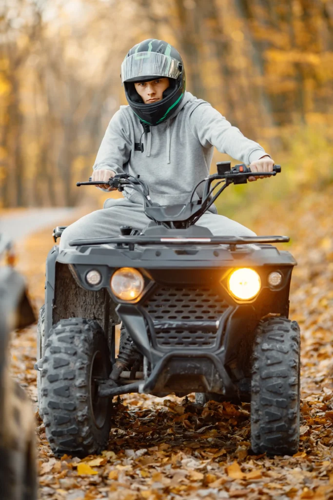 Teenager driving road legal quad bike in Autumn leaves